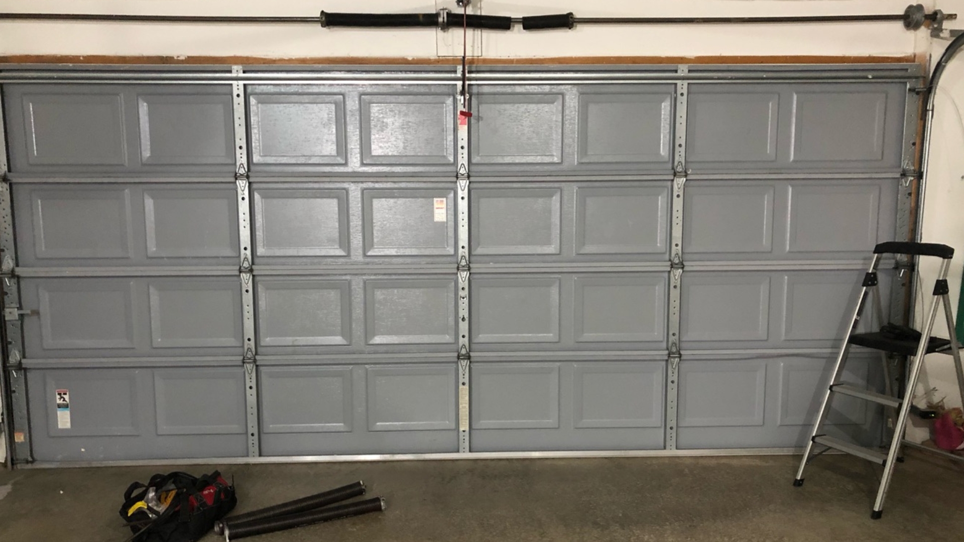 A residential garage door showing its parts like springs, hinges, track and emergency cable