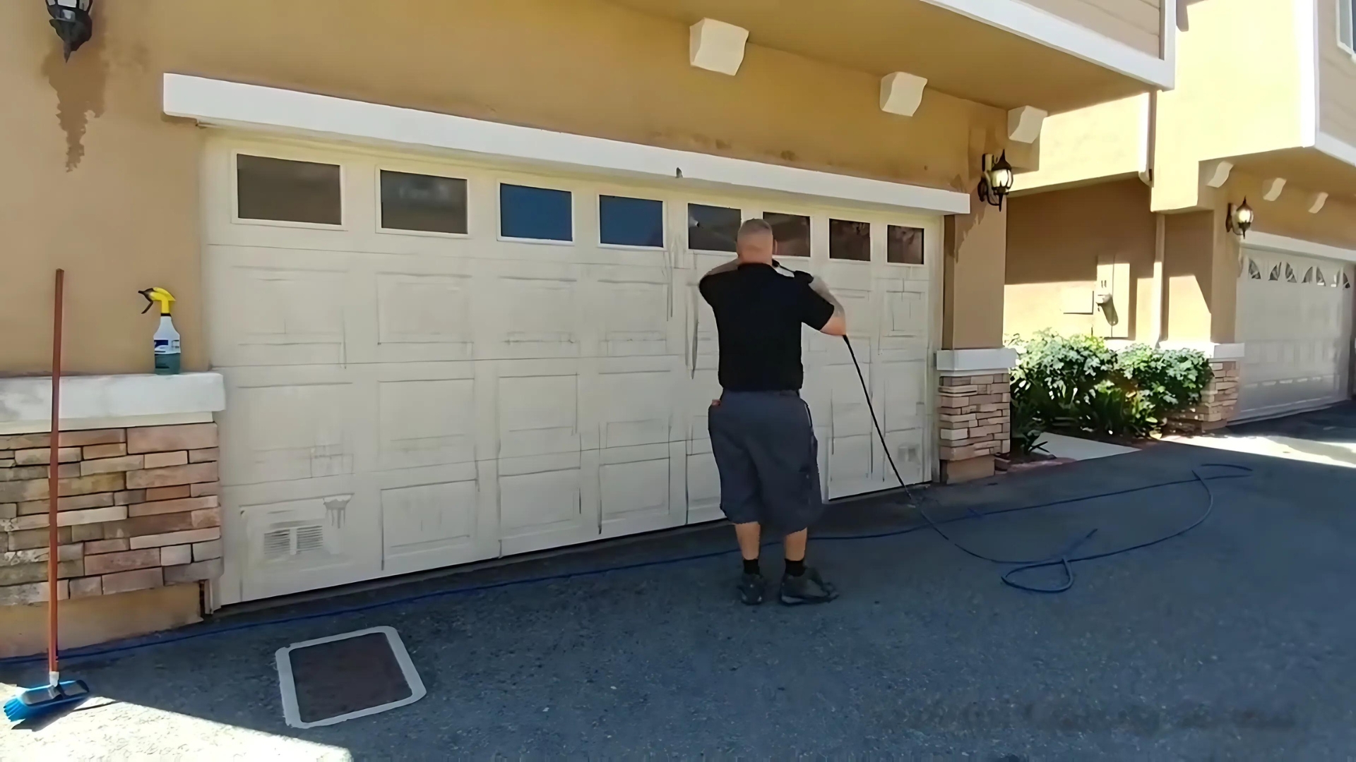 A man cleaning the garage door and removing the rust as part of a maintenance routine