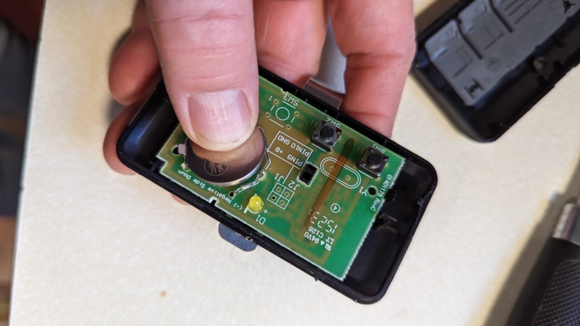 A man holding an open garage door remote showing the battery and internal parts