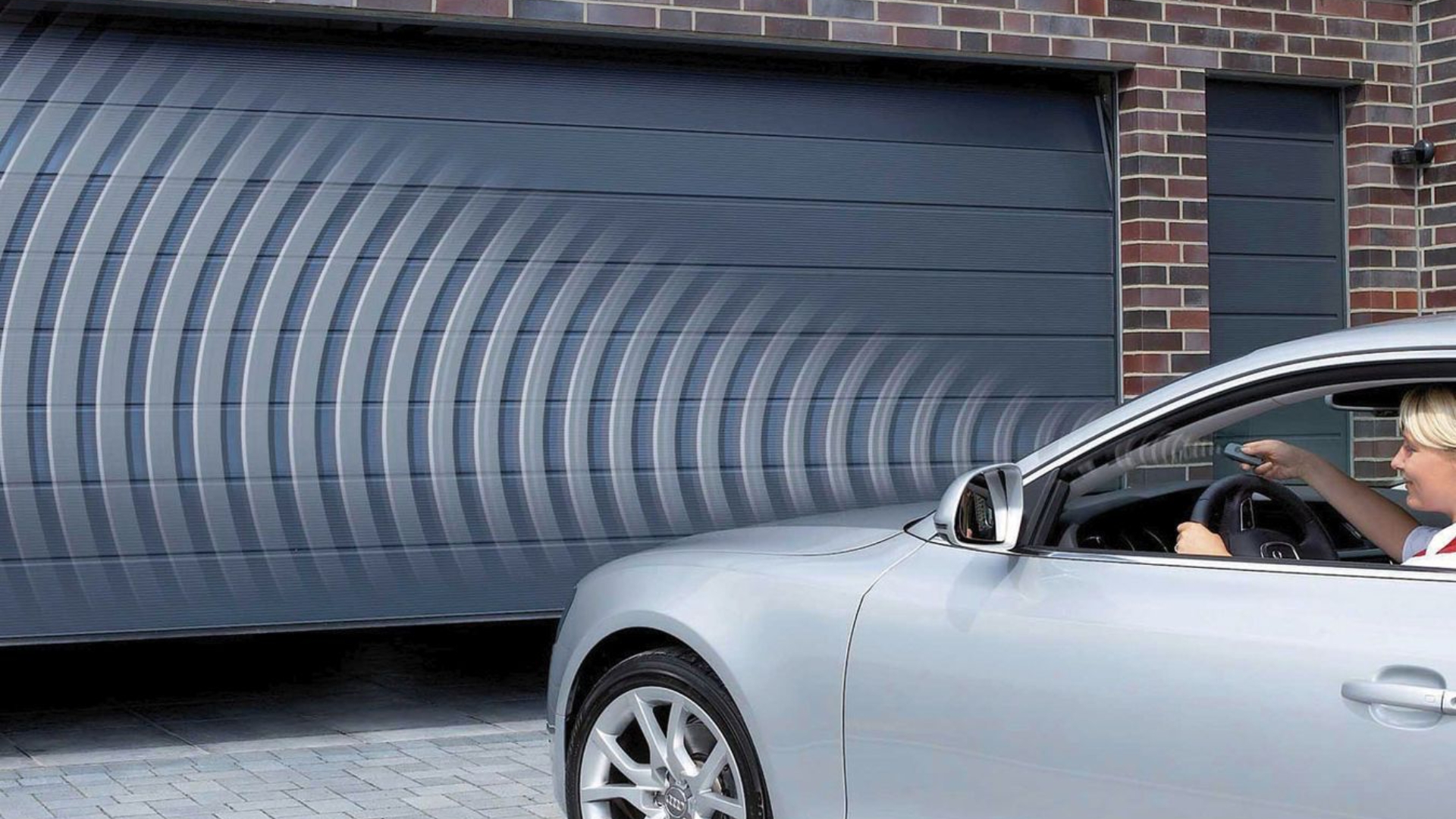 A woman in a car opening the garage door with a remote control