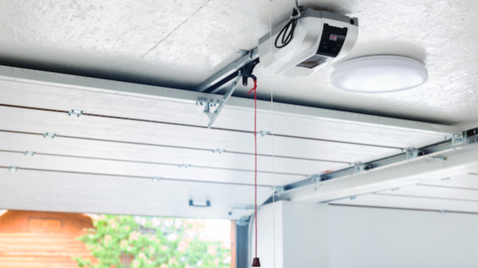 A garage door opener with the red emergency cord hanging