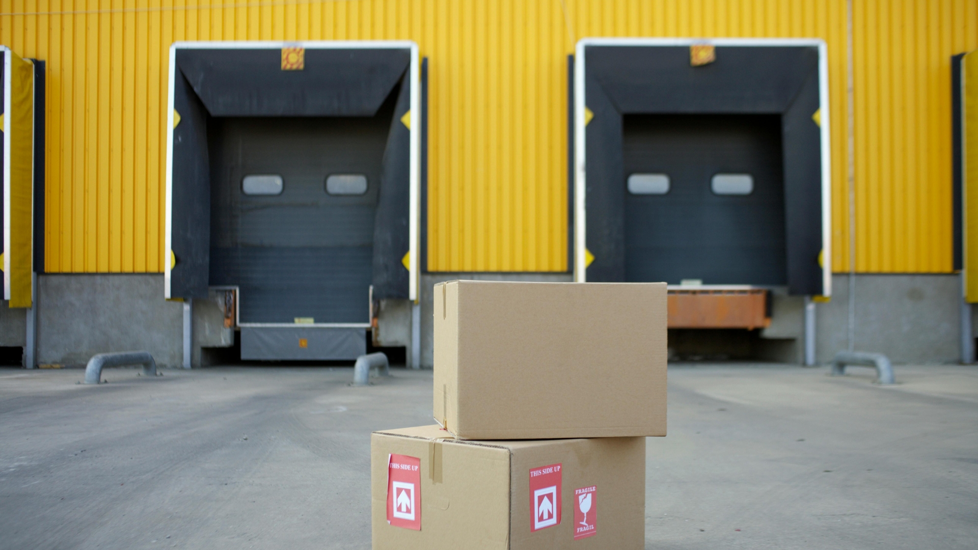 Yellow loading dock doors with protective seals and fragile boxes in the foreground.