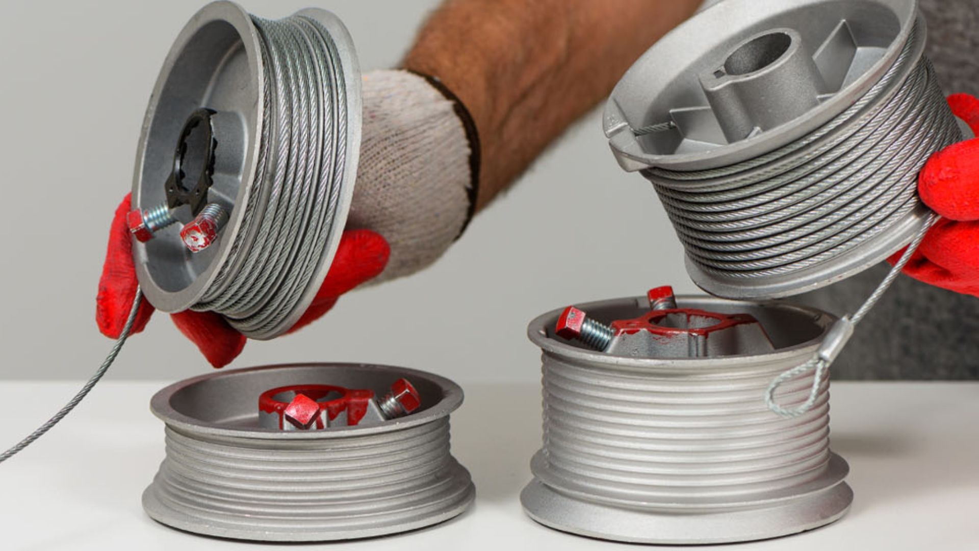 Close-up of garage door cable drums with steel cables attached.