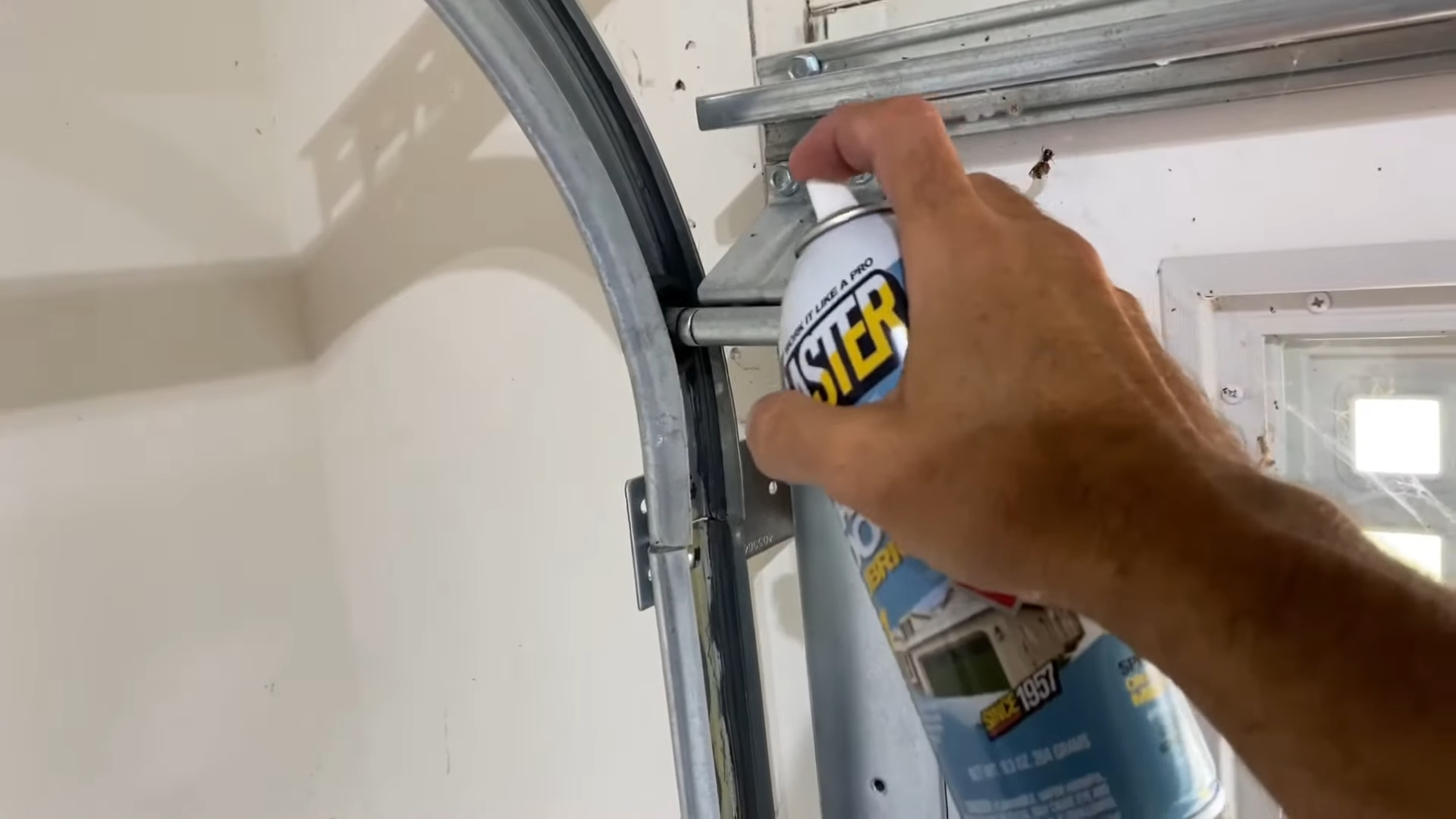 Spraying lubricant to maintain a garage door’s smooth operation.