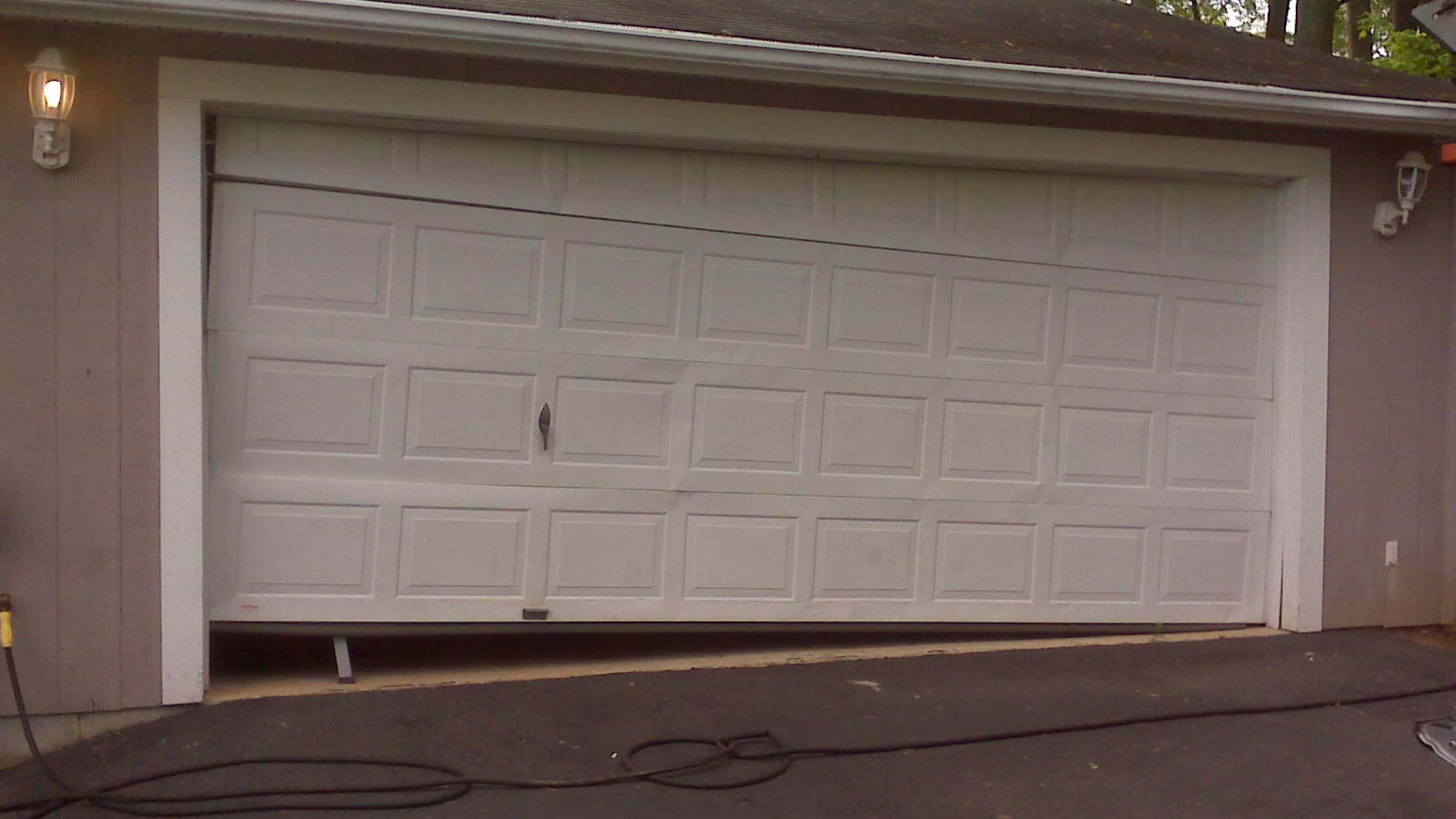 Jammed garage door with visible panel dents. 
