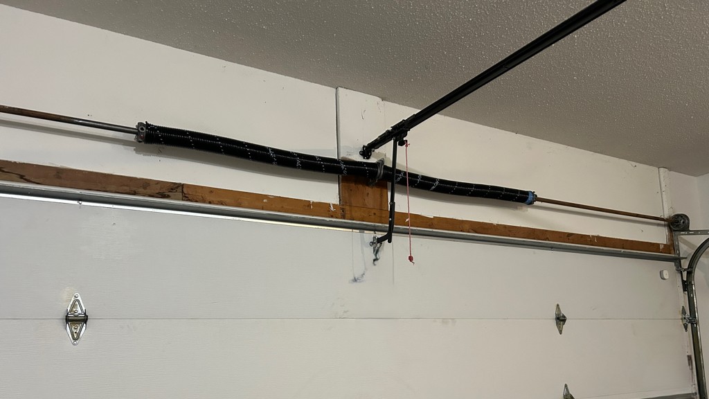 Newly installed torsion spring system mounted above a residential garage door during a garage door spring replacement service.