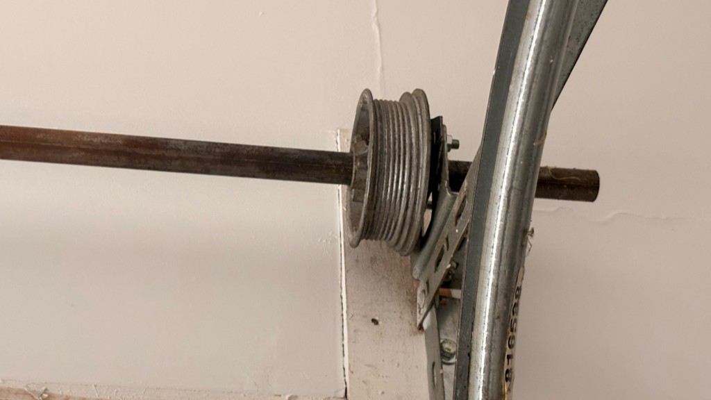 Garage door cable drum and torsion shaft inspected during emergency garage door repair to restore safe and reliable door operation.