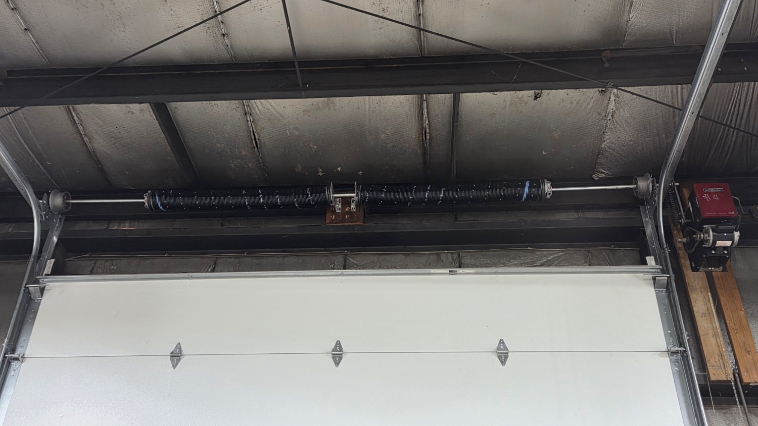 Commercial garage door repair showing torsion springs and overhead door hardware in Des Moines, IA.